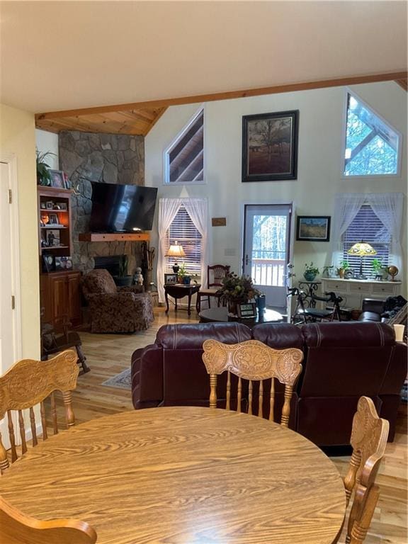 dining area featuring wood finished floors, a towering ceiling, and a fireplace