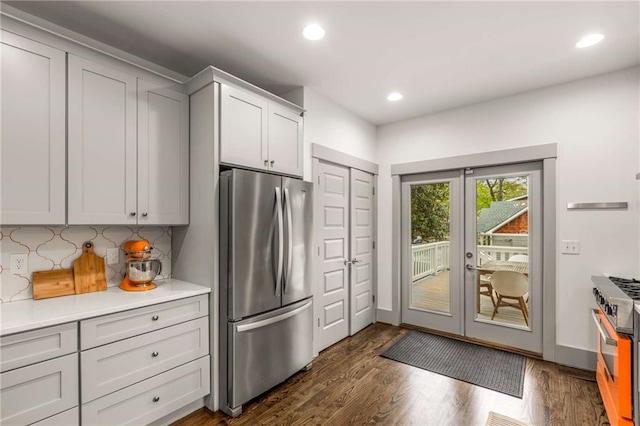 kitchen with decorative backsplash, light countertops, dark wood finished floors, appliances with stainless steel finishes, and french doors