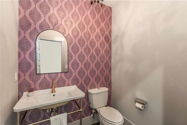 bathroom with a sink, baseboards, and toilet