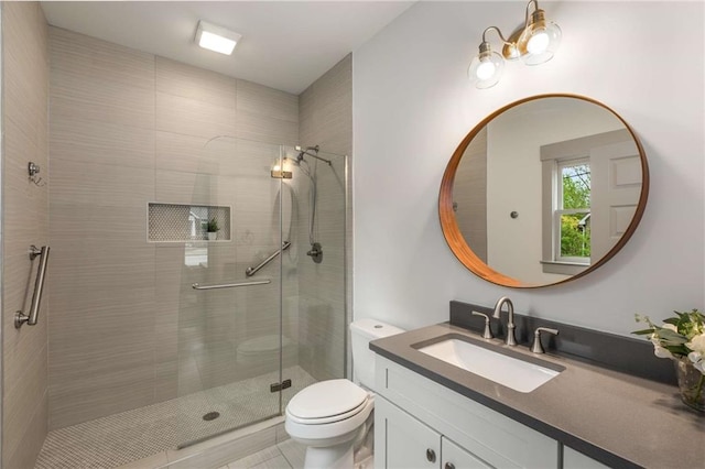 bathroom featuring toilet, a stall shower, and vanity
