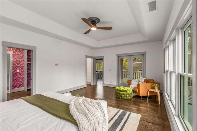 bedroom featuring a tray ceiling, dark wood-type flooring, baseboards, access to exterior, and visible vents