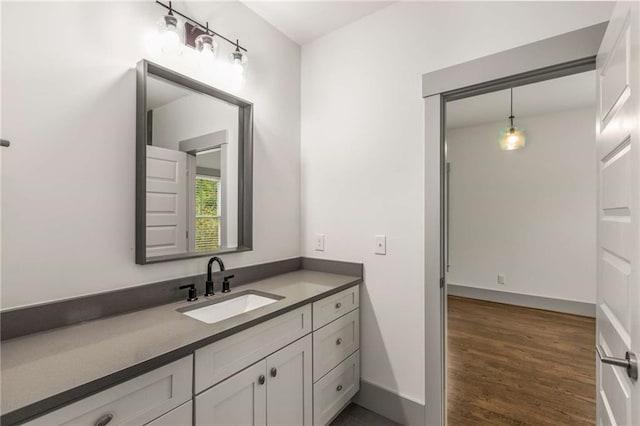 bathroom featuring baseboards, wood finished floors, and vanity