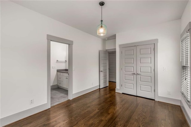 unfurnished bedroom with a closet, baseboards, and wood finished floors