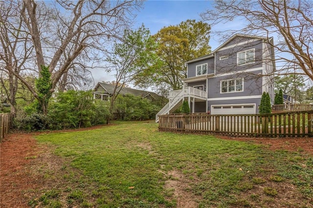 view of yard featuring an attached garage, stairs, and fence private yard