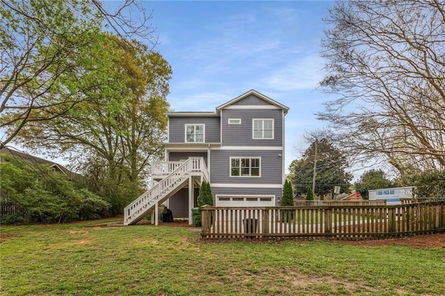 back of property with fence, a wooden deck, an attached garage, stairway, and a yard