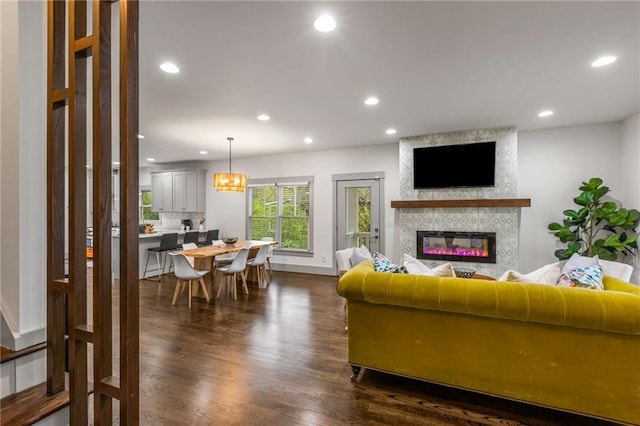 living area with dark wood finished floors, baseboards, recessed lighting, and a large fireplace