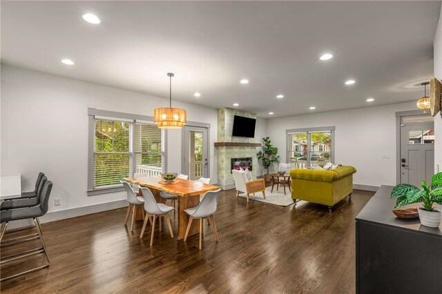 dining room with a large fireplace, recessed lighting, an inviting chandelier, and dark wood finished floors