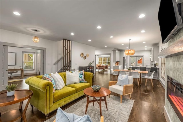 living room with a glass covered fireplace, stairs, recessed lighting, and dark wood-style flooring
