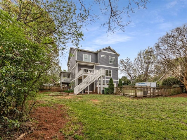 rear view of property with fence, a deck, stairway, and a lawn