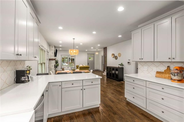 kitchen with open floor plan, light countertops, a peninsula, and dark wood finished floors