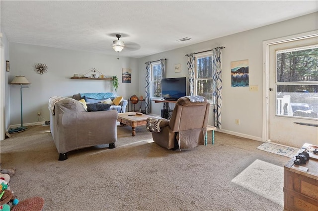 living area with baseboards, ceiling fan, carpet flooring, and a healthy amount of sunlight