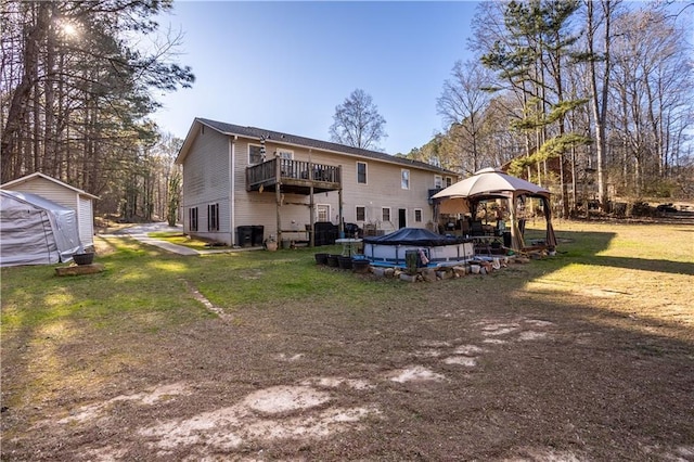 rear view of house with a deck, a gazebo, a lawn, and cooling unit