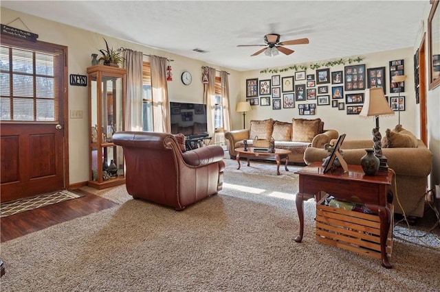 living area with carpet, visible vents, a ceiling fan, wood finished floors, and baseboards