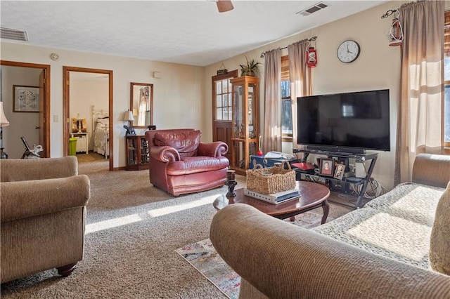 carpeted living area featuring baseboards, visible vents, and a ceiling fan