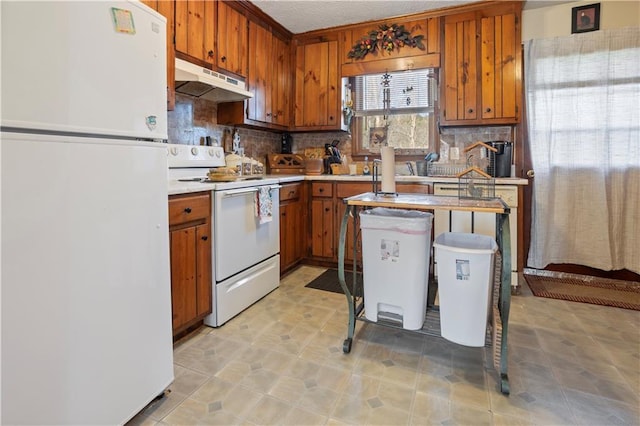 kitchen with under cabinet range hood, white appliances, light countertops, brown cabinets, and decorative backsplash