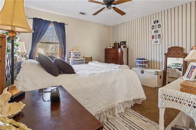 carpeted bedroom featuring a ceiling fan, visible vents, and wallpapered walls