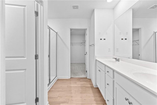 3660 Cattle Field Xing, Loganville, GA 30052 - bathroom with a walk in closet, a shower stall, wood finished floors, and double vanity