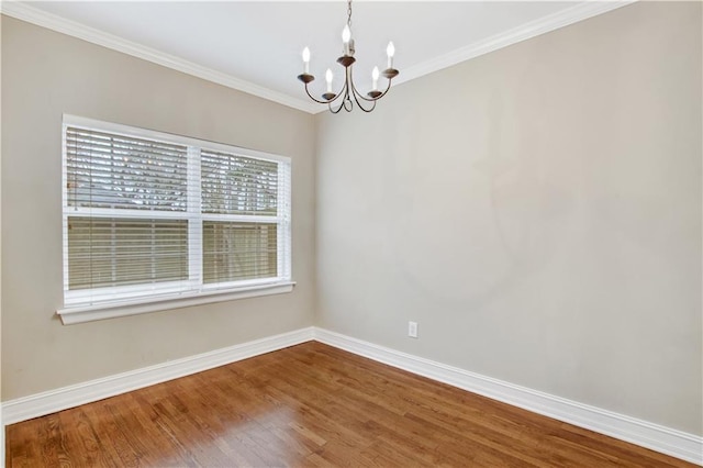 spare room with ornamental molding, wood-type flooring, and an inviting chandelier