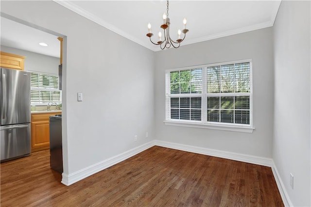 unfurnished dining area with a notable chandelier, dark wood-type flooring, ornamental molding, and sink