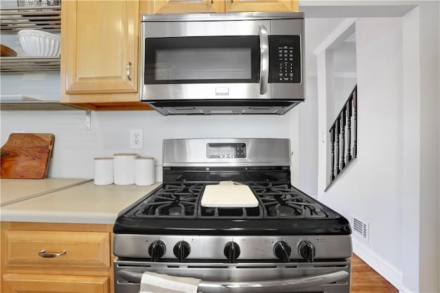 kitchen featuring appliances with stainless steel finishes, dark hardwood / wood-style floors, and light brown cabinetry