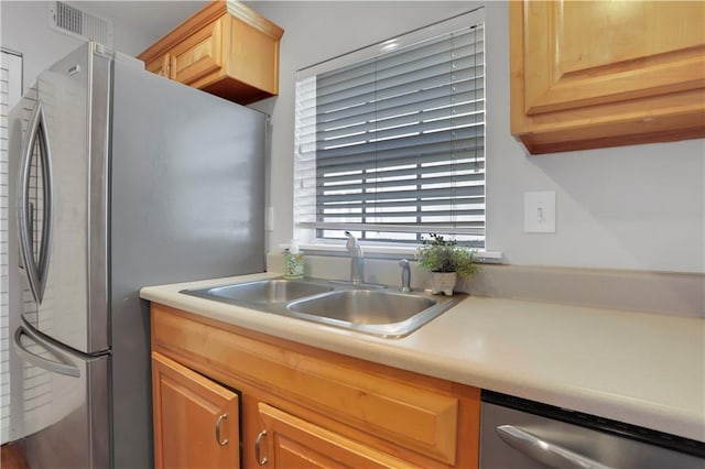 kitchen with appliances with stainless steel finishes, sink, and light brown cabinets