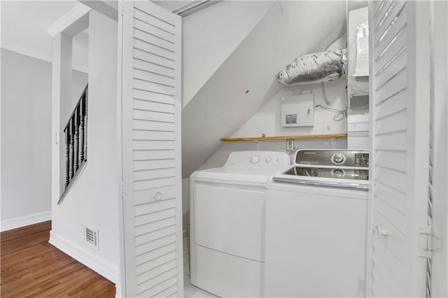 clothes washing area featuring crown molding, washing machine and dryer, and light hardwood / wood-style floors