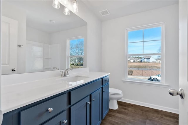 bathroom with wood-type flooring, walk in shower, vanity, and toilet