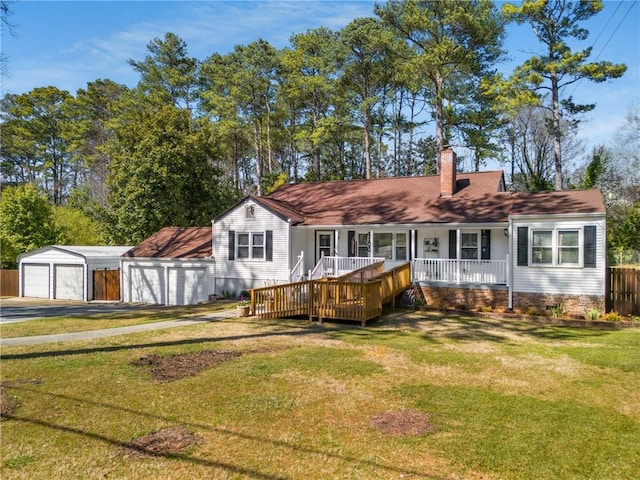 back of house with an outbuilding, a detached garage, a porch, a yard, and a chimney