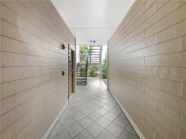 hall with wooden walls and light tile patterned flooring