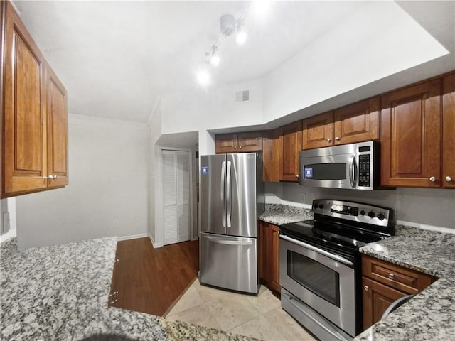200 Renaissance Pkwy NE Unit 302, Atlanta, GA 30308 - kitchen with brown cabinetry, light stone countertops, visible vents, and appliances with stainless steel finishes