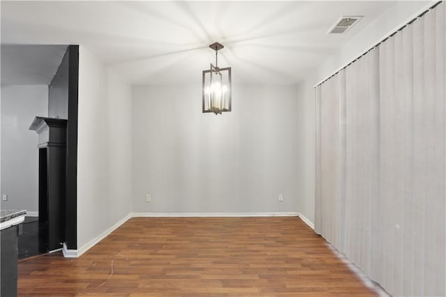 unfurnished dining area featuring wood finished floors, baseboards, and a chandelier