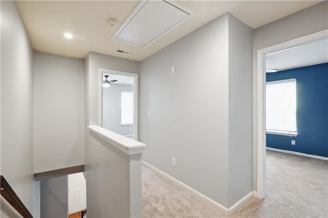 hallway featuring attic access, an upstairs landing, carpet floors, and baseboards