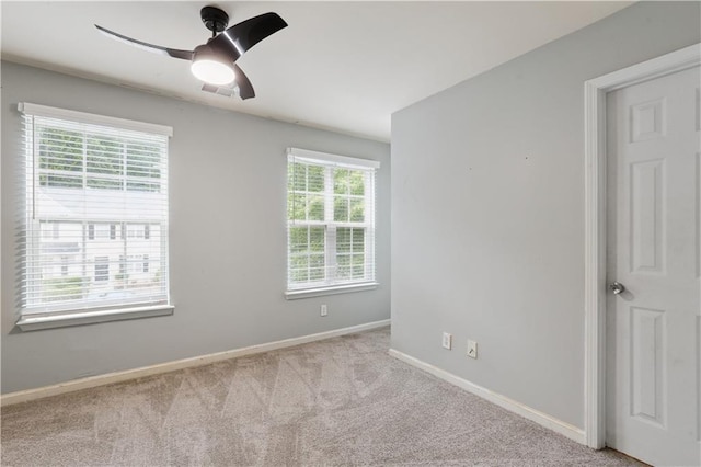 carpeted spare room featuring baseboards and ceiling fan
