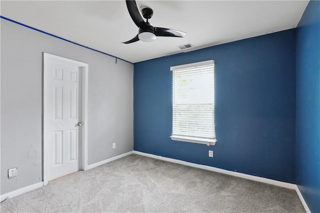 carpeted spare room with a ceiling fan and baseboards