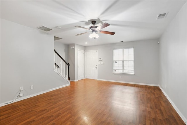 spare room featuring stairs, ceiling fan, wood finished floors, and baseboards