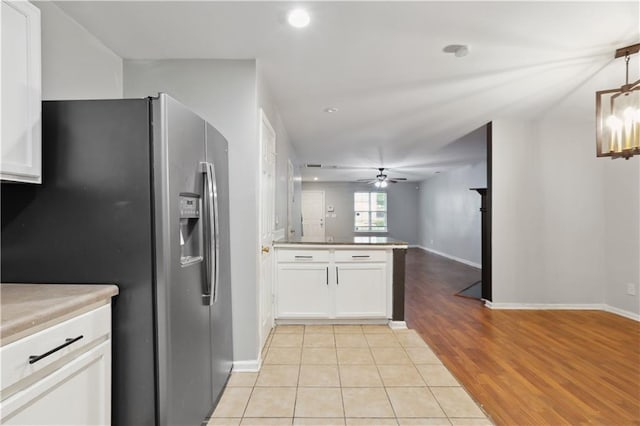 kitchen with stainless steel refrigerator with ice dispenser, a peninsula, a ceiling fan, white cabinets, and light wood-style flooring