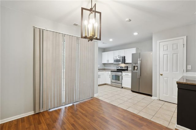 kitchen featuring stainless steel appliances, white cabinetry, a chandelier, light countertops, and baseboards
