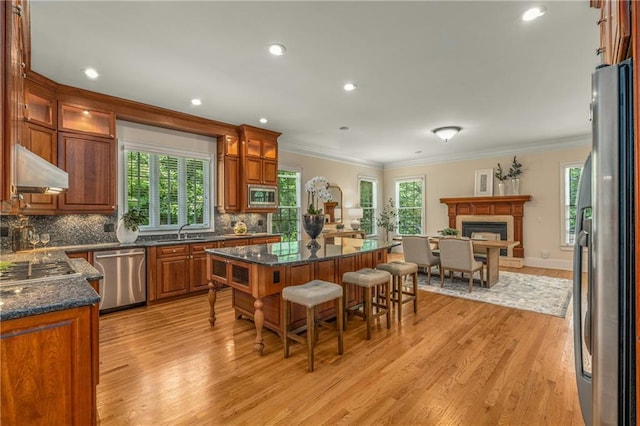 1655 Arrowhead Trl NE, Atlanta, GA 30345 - kitchen featuring appliances with stainless steel finishes, under cabinet range hood, ornamental molding, light wood-style floors, and a kitchen bar