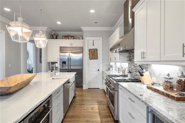 kitchen with white cabinetry, premium appliances, pendant lighting, and crown molding