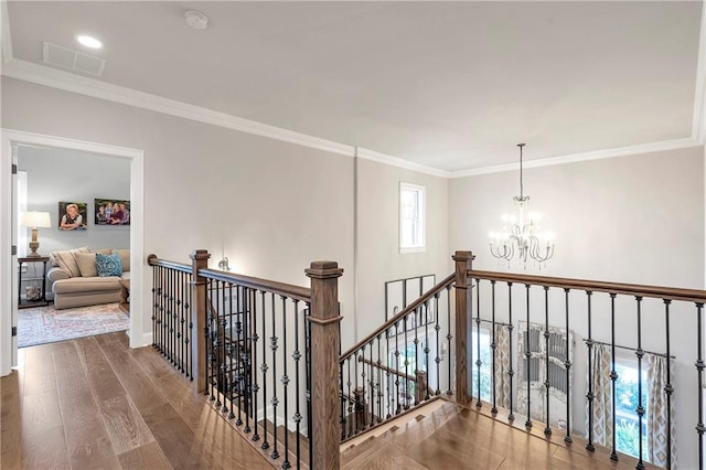 hallway with wood-type flooring, crown molding, and a notable chandelier