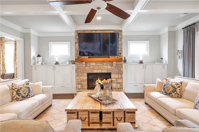 living room with a stone fireplace, a wealth of natural light, light hardwood / wood-style floors, and coffered ceiling