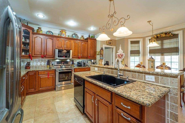 kitchen with appliances with stainless steel finishes, a kitchen island with sink, sink, decorative light fixtures, and a breakfast bar area