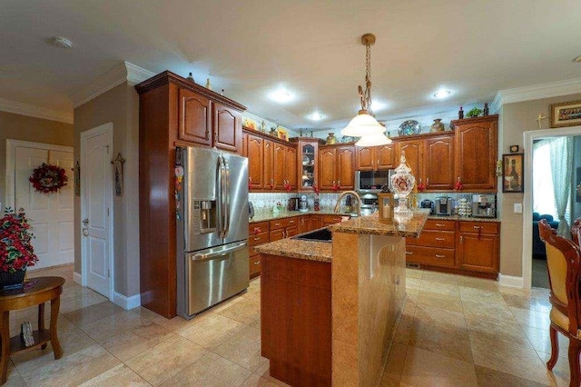 kitchen with light stone countertops, tasteful backsplash, sink, stainless steel fridge, and a kitchen island with sink