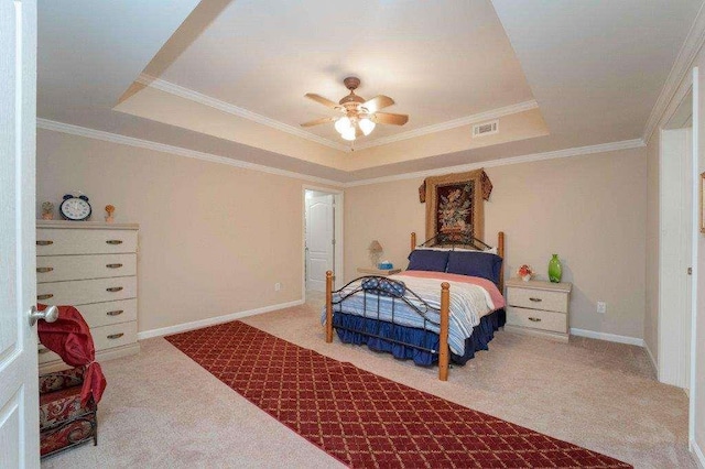 carpeted bedroom with ceiling fan, a tray ceiling, and ornamental molding