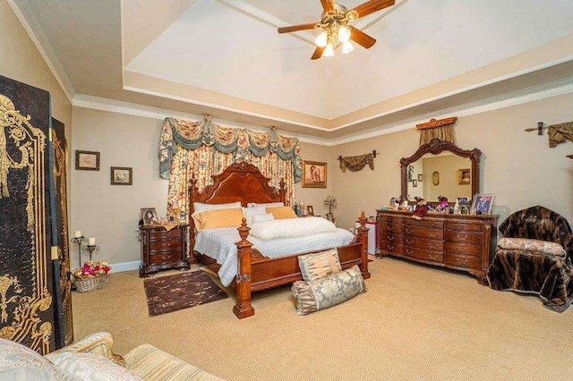 carpeted bedroom with ceiling fan, a tray ceiling, and crown molding