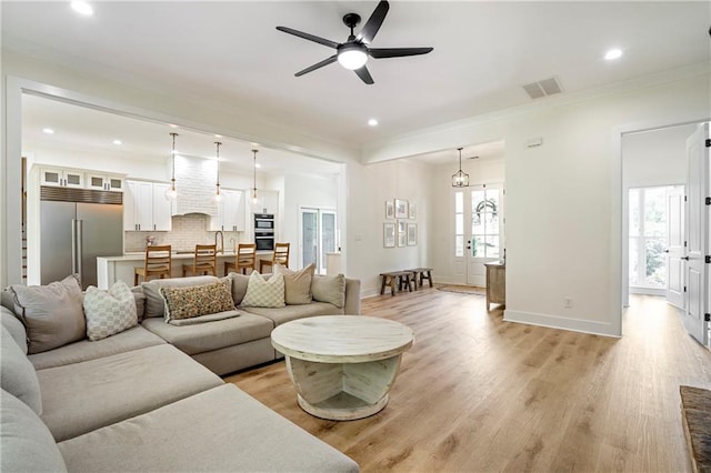 living room with crown molding, ceiling fan, light wood-type flooring, and a wealth of natural light