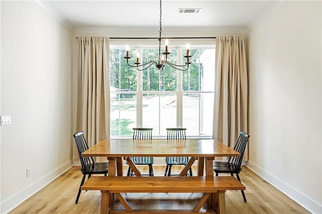 dining room with ornamental molding, a notable chandelier, and light wood-type flooring