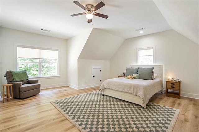 bedroom featuring vaulted ceiling, light hardwood / wood-style flooring, multiple windows, and ceiling fan