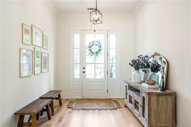 entrance foyer featuring light hardwood / wood-style floors, ornamental molding, and plenty of natural light