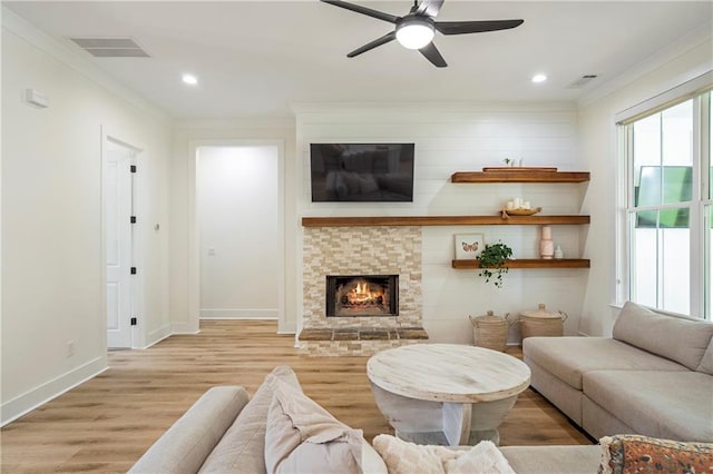 living room featuring light hardwood / wood-style flooring, ornamental molding, a fireplace, and ceiling fan